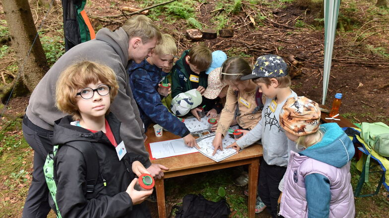 Bastian Henke zeigt den Altenberger Drittklässlern, was sie im Waldboden gefunden haben.