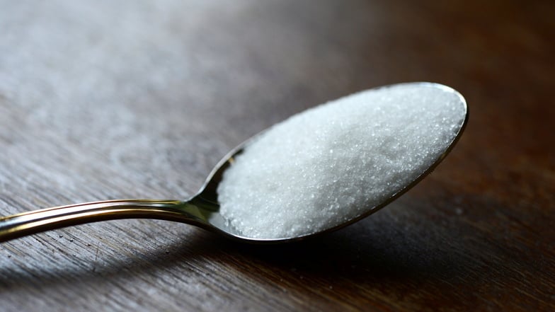Ein Löffel mit Haushaltszucker: Hersteller von Fertigprodukten haben zugesichert, schrittweise Salz, Zucker und Fett in Rezepturen zu reduzieren.