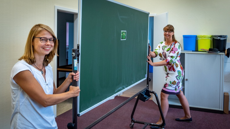 Tina Jentzsch (links), die pädagogische Leiterin, und Schulleiterin Susann Gasse schieben eine Tafel in Position. Die Möbel für den Start hat die Schule gespendet bekommen.