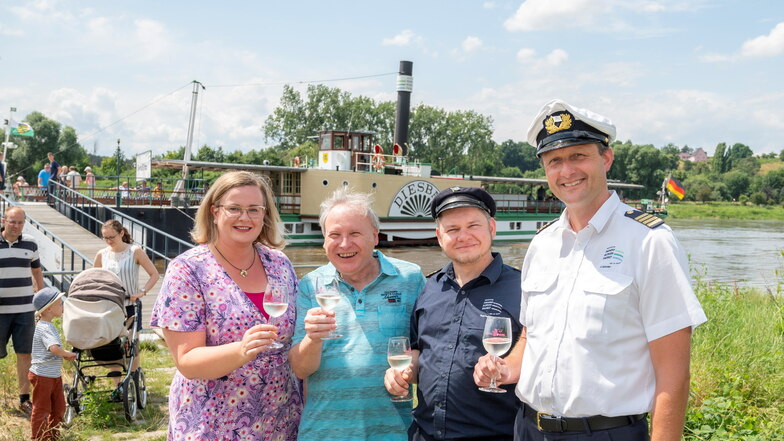 (V.l.n.r.) Die ehemalige sächsische Weinkönigin Maria Lehmann und Bürgermeister Gerd Barthold begrüßen Maschinist Falk Hering und Kapitän Jan Schröter an Land mit einem Glas Secco.