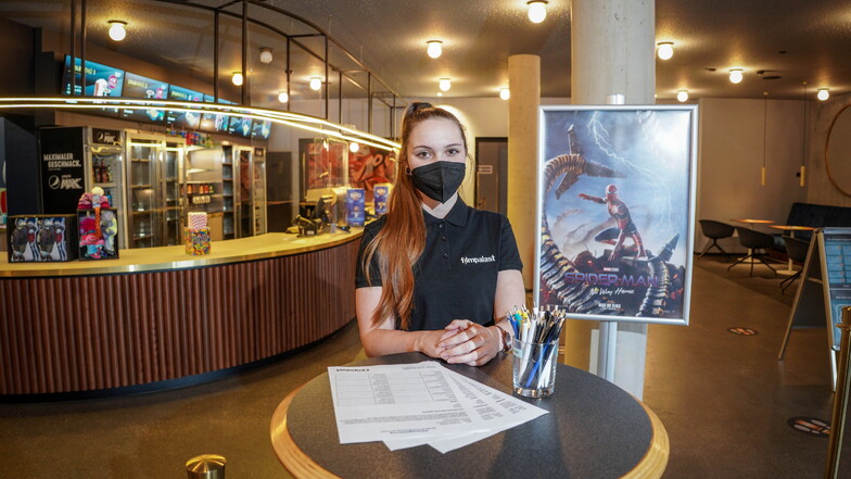 Der Bautzener Filmpalast zeigt ab Freitag wieder Kinofilme, etwa den neuen Spiderman. Mitarbeiterin Celine Biller hat im Foyer schon die Bögen zur Kontakterfassung für die Besucher vorbereitet.