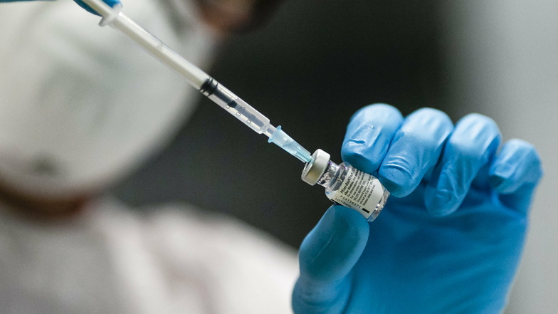 Schleswig-Holstein, Kiel: Eine Mitarbeiterin des Impfzentrums zieht mit einer Kanüle den Impfstoff aus einer Glasampulle auf.