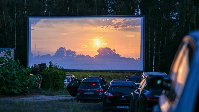 Autos stehen in der Dämmerung in einem Autokino