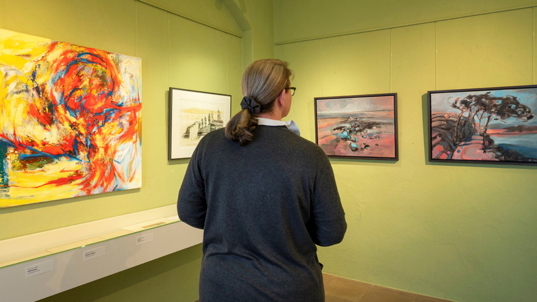 Eine Besucherin betrachtet Bilder in der aktuellen Ausstellung des Künstlerinnen-Trios.