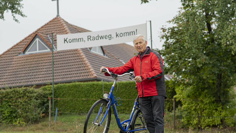 Zwischen Kamenz und Gersdorf klafft noch immer eine Lücke im Radweg. Pastor Wilfried Krause mahnt mit einem Transparent, dass endlich etwas passiert.