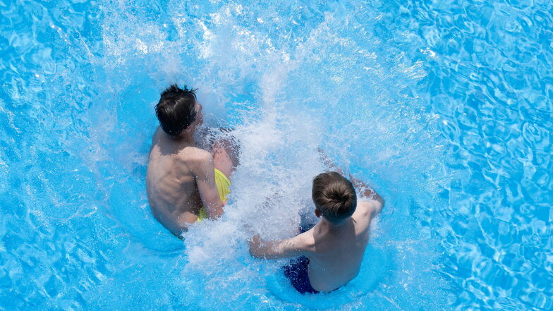 Zwei Jungen springen im Freibad Zacke vom Beckenrand ins Wasser.