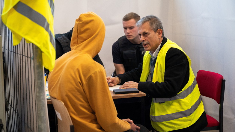 Ein Dolmetscher (rechts) hilft bei der Befragung eines Migranten in der Kontrolleinheit am Grenzübergang Ludwigsdorf in Görlitz.