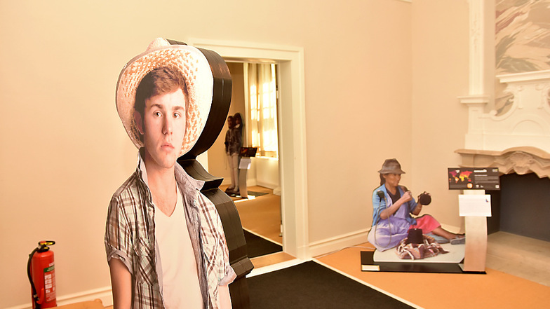 Die Hörstationen der Klimaausstellung sind an lebensgroße Fotos von Menschen angeschlossen: Vorn ein Bauer aus den USA, hinten eine Frau aus Bolivien.