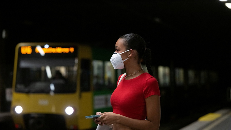 Eine Frau trägt in einer Straßenbahnhaltestelle eine FFP2-Maske.
