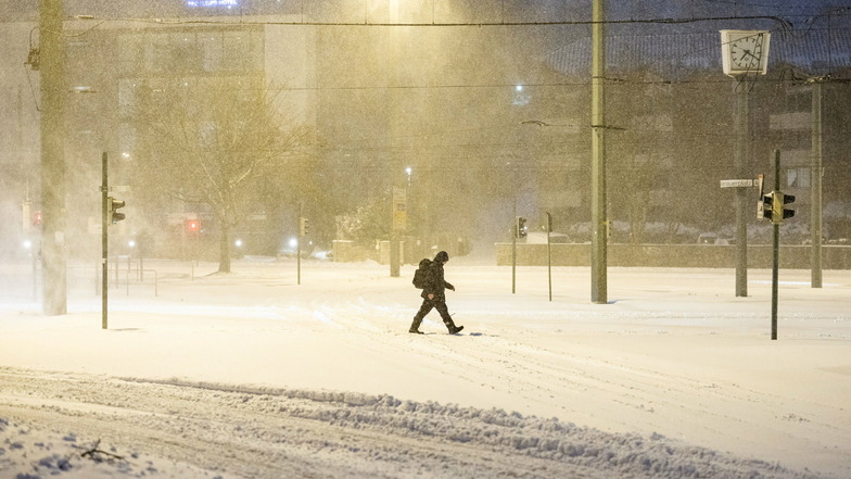 Nordrhein-Westfalen, Bielefeld: Ein Mann geht über eine zugeschneite Straße.