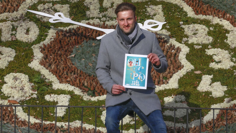 Vor der Zittauer Blumenuhr: Redakteur Thomas Christmann hält einen Ausdruck des Posters in den Händen vom diesjährigen "Spiel mit versteckten Schätzen".