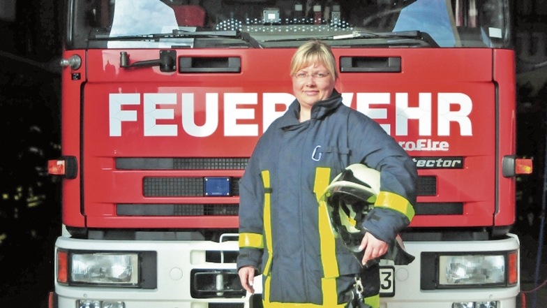 Katja Kümmig in Einsatzkleidung vor einem der Großenhainer Feuerwehrfahrzeuge.