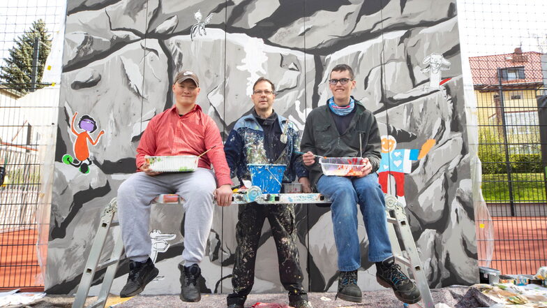 Der Döbelner Graffiti-Künstler Frank Schäfer (Mitte) hat mit den Schülern Pascal (links) und Jeffry als Praktikanten in dieser Woche die Boulderwand der Regenbogenschule bemalt.