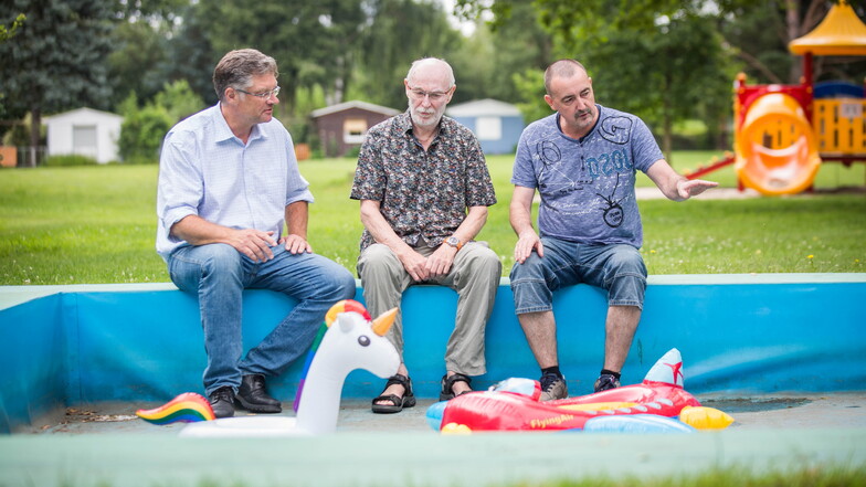 Holger Zastrow (l.) sieht sich mit Siedler Uwe Danusch (r.) und Steffen Nitzsche, dem Vater einer Siedlerin, das kaputte Kinderbecken an.