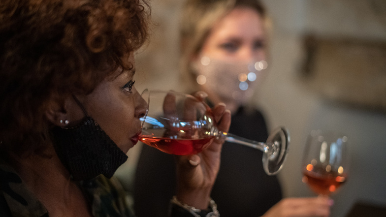 Sachsens Winzer leiden unter Umsatzausfällen durch die Corona-Auflagen. Langsam bessert sich die Lage: Ein weiblicher Gast trinkt in einer Dresdner Bar aus einem Glas Wein.