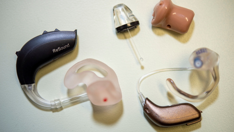 Zwei Beispiele für Hinter-Ohr-Hörsystem links und rechts sowie ein Im-Ohr-Hörsystem oben.