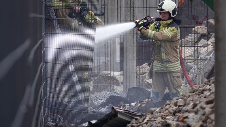 Ein Feuerwehrmann löscht brennendes Pappelholz in der Südvorstadt.