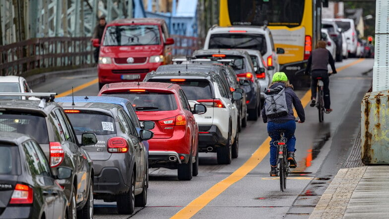 Radfahrer fahren über das Blaue Wunder auf einem markierten Radweg an Autos im Stau vorbei. Die FDP fordert das Ende solcher Einschränkungen für Autofahrer.