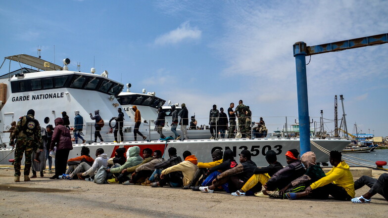 Migranten, die von der tunesischen Marine-Nationalgarde im Mittelmeer abgefangen wurden, warten im Hafen von Sfax.