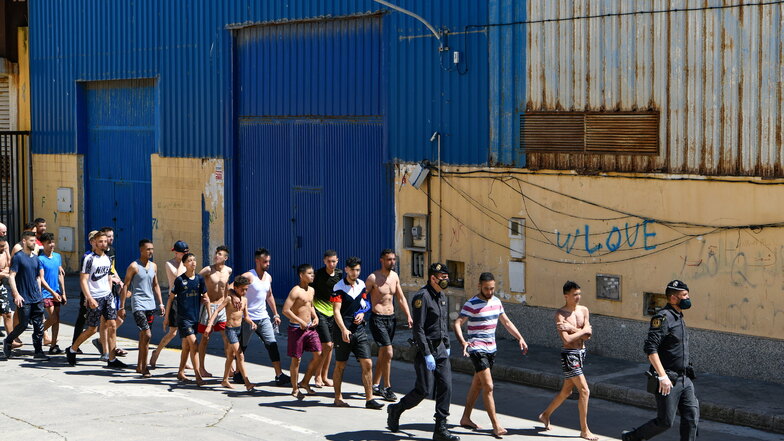 Eine Gruppe junger Migranten wird in der spanischen Nordafrika-Exklave Ceuta von Polizisten eskortiert.