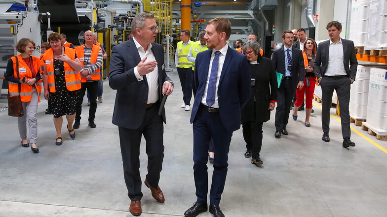 Bei der Eröffnung der neuen Produktionsstätte der Firma Bauder in Schwepnitz lässt sich Sachsens Ministerpräsident Michael Kretschmer (vorn r.) von Werksleiter Andreas Pohontsch die Fertigung erklären.