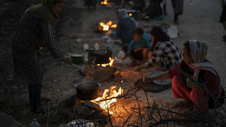 Migranten sitzen an einer Straße in der Nähe der Stadt Mytilene auf Lesbos um kleine Feuer und bereiten Essen zu. Nach dem Feuer im Flüchtlingslager Moria waren mehr als 12.000 Menschen obdachlos geworden.