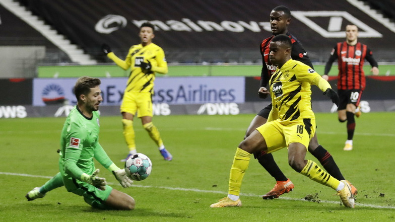Dortmunds Youssoufa Moukoko (M) versucht gegen die Frankfurter Kevin Trapp (l) und Evan Ndicka (r) an den Ball zu kommen.