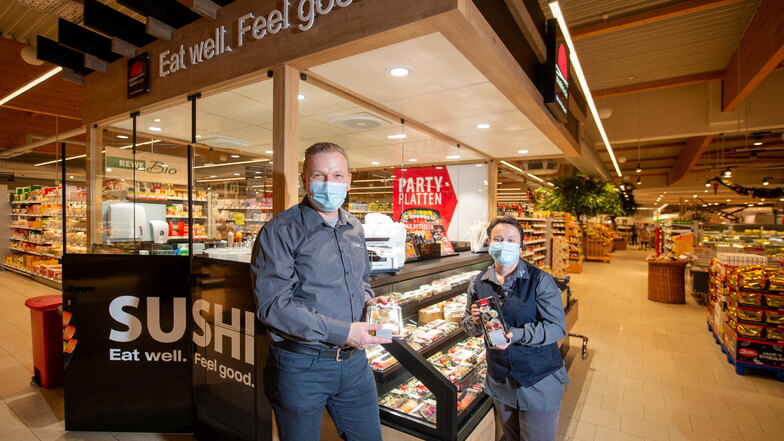 Der Inhaber des Rewe-Marktes im Löma-Center Björn Keyser (l.) steht mit seiner und Marktleiterin Jacqueline Irmer vor dem neuen Sushi-Stand. Dort werden japanische Fischspezialitäten frisch zubereitet.