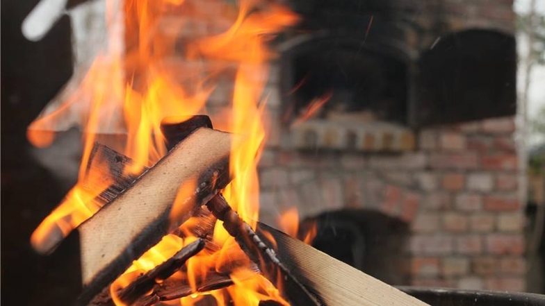 Im Grill flackern die Flammen fürs Anheizen der großen Holzscheite.