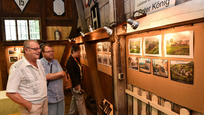 Besucher aus Liebstadt schauen sich in dem normalerweise verschlossenen ehemaligen Güterschuppen Bilder von Peter König an.