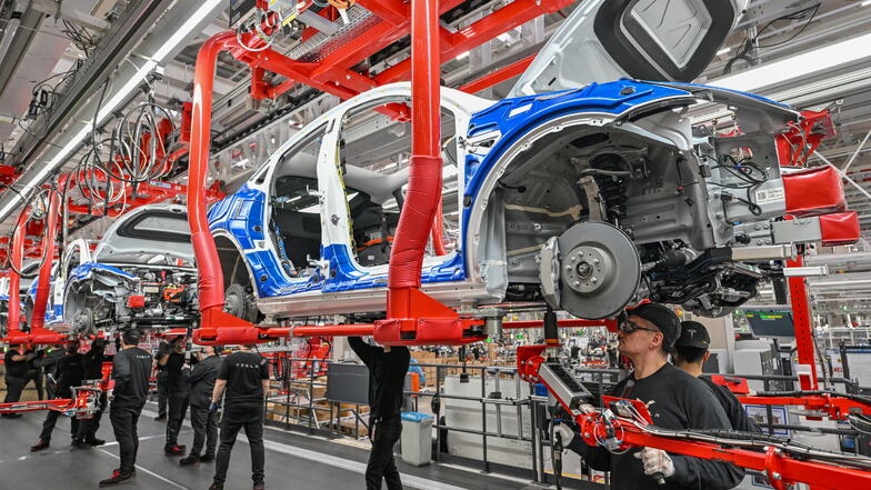 Mitarbeiter der Tesla Gigafactory in Grünheide arbeiten an einer Fertigungslinie eines Elektrofahrzeuges vom Typ Model Y.