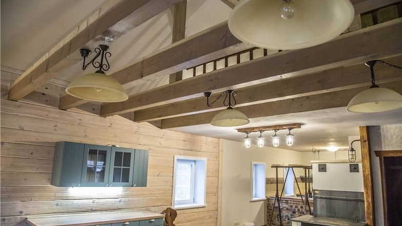Durch die Balken ist der Blick frei ins Dachgeschoss. Der Küchenofen hat ein nagelneues Innenleben, außen alte Kacheln und kann mit Holz gefeuert werden.