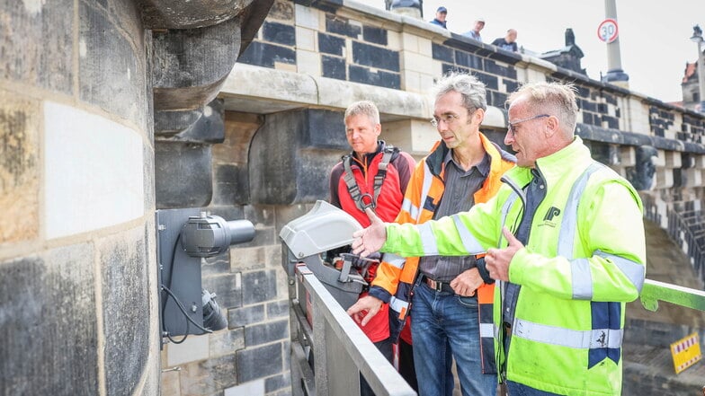 Abteilungsleiter Holger Kalbe (M.) und Bauleiter Karsten Engelmann (r.) von den Sächsischen Sandsteinwerken inspizieren zum Abschluss die letzten Stellen an der Augustusbrücke, die erneuert wurden. Hubbühnenführer Frank Marten bugsiert sie dorthin.