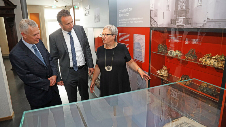 Museums-Chefin Maritta Prätzel erklärt Riesas Oberbürgermeister Marco Müller (CDU, M.) und Sparkassenvorstand Rainer Schikatzki die Objekte aus der Klostergruft, die in der Dauerausstellung zu besichtigen sind.