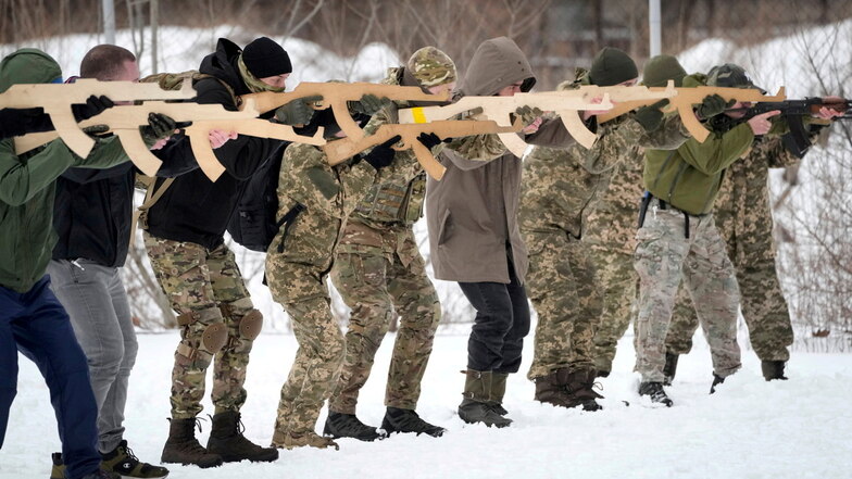 Mitglieder der ukrainischen Territorialen Verteidigungskräfte, einer freiwilligen Militäreinheit der Streitkräfte, trainieren in der Nähe der Stadt mit Holzattrappen als Gewehr.