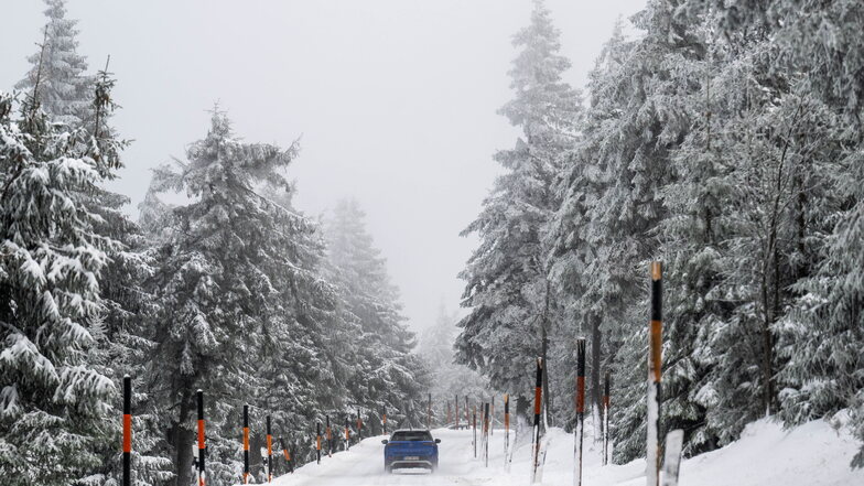 Ein Auto fährt bei Oberwiesenthal durch die verschneite  Landschaft.