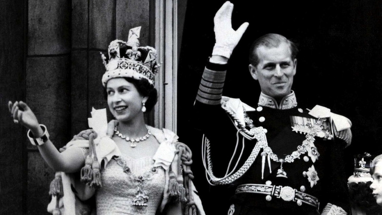 1953: Königin Elizabeth II. und Prinz Philip winken nach der prunkvollen Krönungszeremonie in der Westminster-Abtei vom Balkon des Buckingham Palasts den Menschen zu.