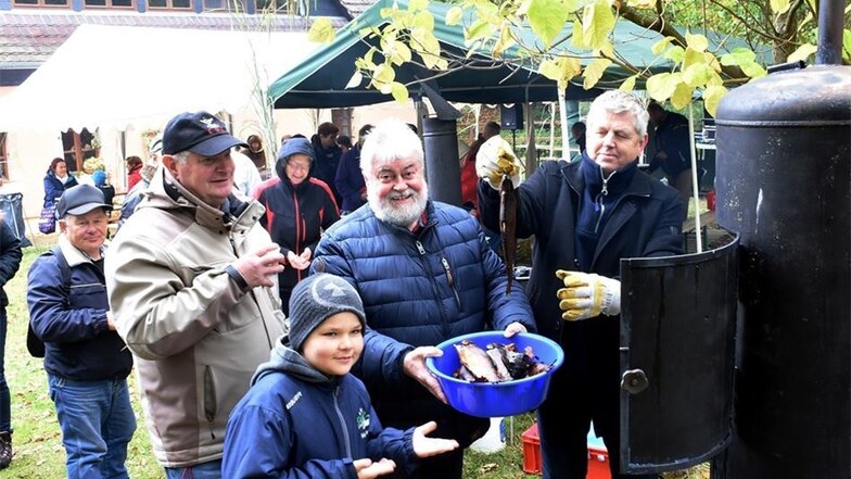 Ulrich Dedeleit (Bildmitte) und Günter Schuster versorgen die Gäste während der Kirmes am Sonntagvormittag in Thiemendorf mit frisch geräuchertem Fisch.