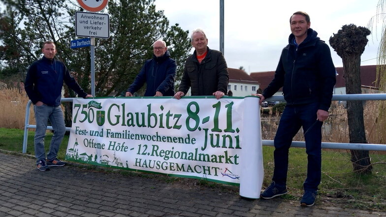 Am Glaubitzer Dorfteich haben Bürgermeister Lutz Thiemig (2.v.r.) und einige seiner Mitstreiter das erste Werbebanner für die 750-Jahrfeier vom 8. bis 11. Juni angebracht.