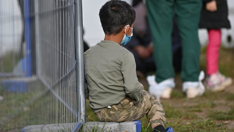 Ein Junge sitzt an einem Zaun in der Zentralen Erstaufnahmeeinrichtung für Asylbewerber in Eisenhüttenstadt.