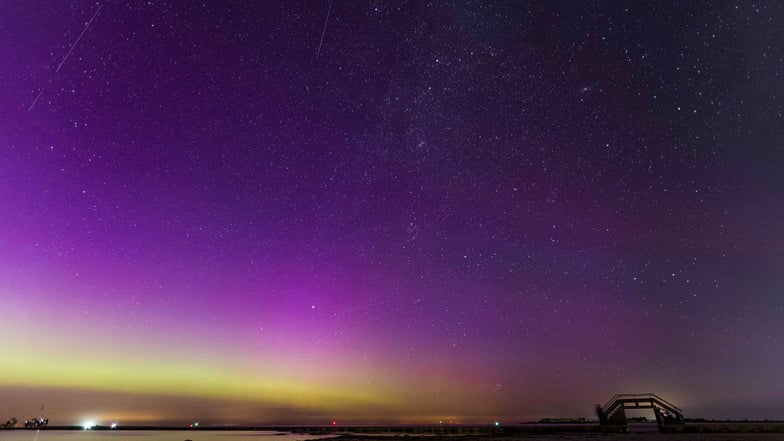 Polarlichter und eine Sternschnuppe der Perseiden sind bei sternenklarer Nacht über der Ostsee zu sehen.