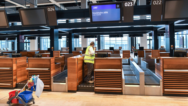 Eine Angestellte einer Reinigungsfirma säubert einen Check-in-Schalter im Terminalgebäude des Hauptstadflughafens Berlin Brandenburg Willy Brandt (BER).