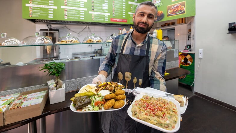 Die Hände voller Sattmacher: Hamza Alomayer, einer der vier Brüder hinter dem Lokal Omas Haus, mit vollen Tellern.