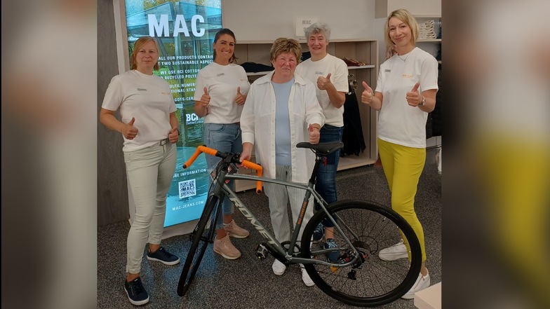 Karin Dennerlein (Mitte) bekommt von den Mitarbeitern des Großschönauer Ladens das Fahrrad überreicht.
