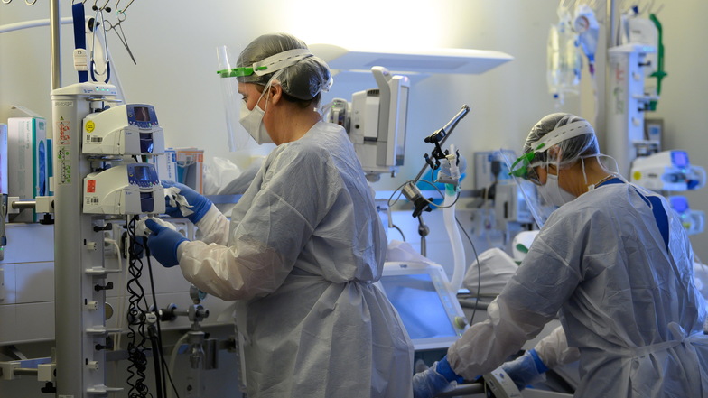 Intensivpflegerinnen sind in Schutzkleidungen auf der Covid-19-Intensivstation einer Klinik in Pulsnitz mit der Versorgung von Corona-Patienten beschäftigt.