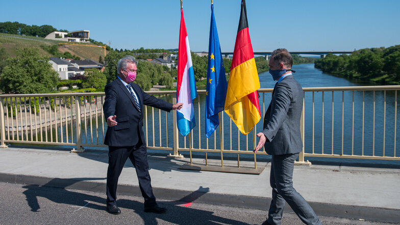 Jean Asselborn (l) und Heiko Maas (SPD) trafen sich auf der Brücke über die Mosel, die das saarländische Perl und das Luxemburger Schengen verbindet. In der Nacht wurden die Grenzen zwischen Deutschland und Luxemburg wieder geöffnet.