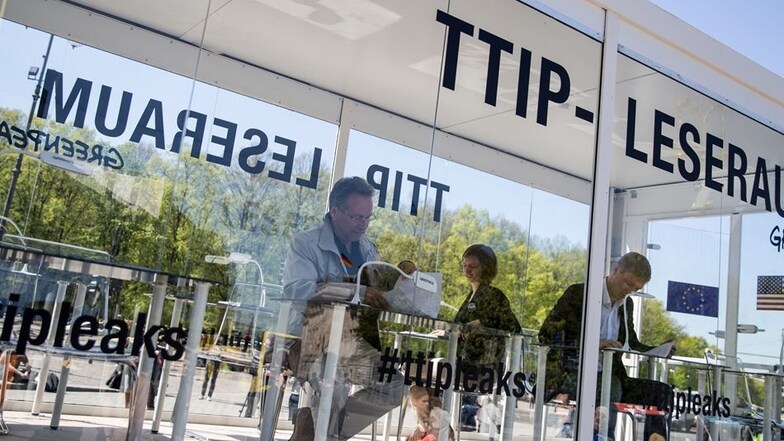 Der Bundestagsabgeordnete Klaus Ernst von der Partei Die Linke blättert in dem gläsernen Leseraum in den von Greenpeace veröffentlichten TTIP-Dokumenten.