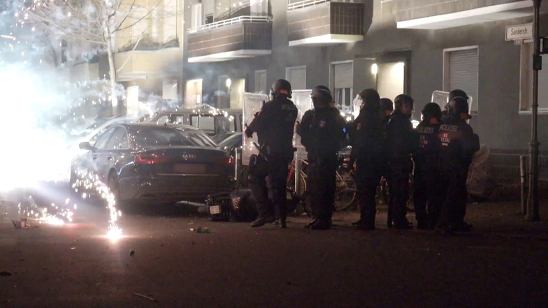 Polizeibeamte stehen in der Silvesternacht hinter explodierendem Feuerwerk. Nicht nur in der Hauptstadt kam es zu Attacken auf die Einsatzkräfte.