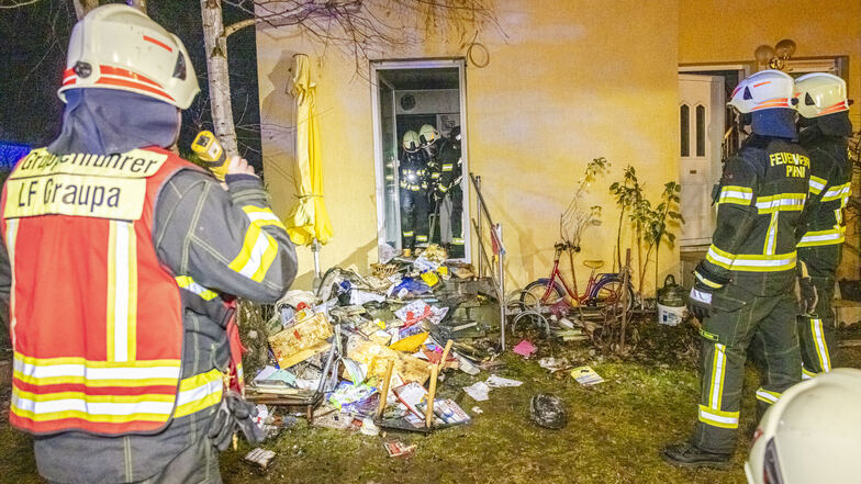 Feuerwehrleute vor dem Einfamilienhaus in Graupa: Das Gebäude ist nach dem Brand unbewohnbar.
