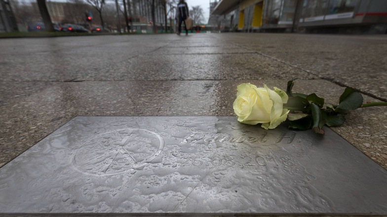 Eine Rose und Wassertropfen liegen auf einer Gedenkplatte für den getöteten Daniel H. in Chemnitz.